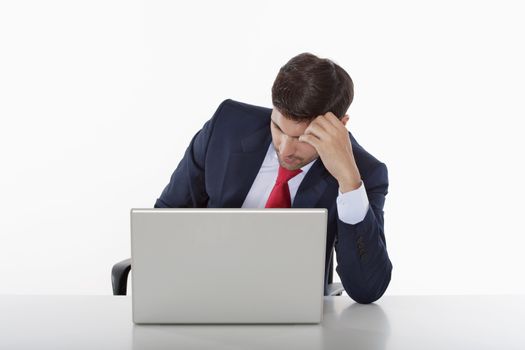 worried business executive in suit behind desk with laptop