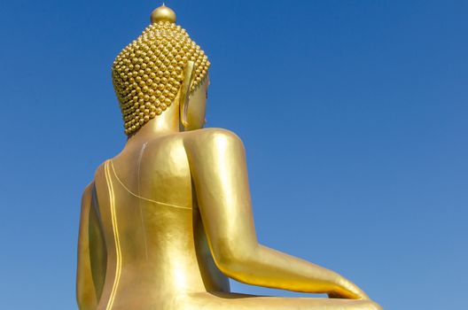 Back side of golden buddha with deep blue sky background