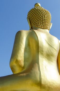 Back side of golden buddha with deep blue sky background