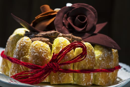 Beautifully decorated chocolate cake topped with roses on cocoa icing and surrounded with freshly baked golden pastries for a delicious dessert or sweet