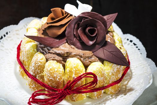 Beautifully decorated chocolate cake topped with roses on cocoa icing and surrounded with freshly baked golden pastries for a delicious dessert or sweet