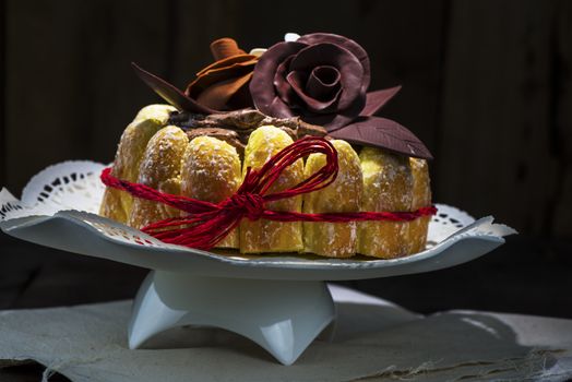 Beautifully decorated chocolate cake topped with roses on cocoa icing and surrounded with freshly baked golden pastries for a delicious dessert or sweet