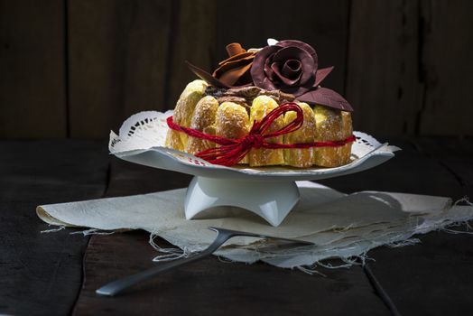 Beautifully decorated chocolate cake topped with roses on cocoa icing and surrounded with freshly baked golden pastries for a delicious dessert or sweet