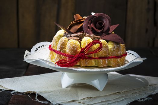 Beautifully decorated chocolate cake topped with roses on cocoa icing and surrounded with freshly baked golden pastries for a delicious dessert or sweet