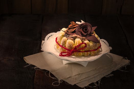 Beautifully decorated chocolate cake topped with roses on cocoa icing and surrounded with freshly baked golden pastries for a delicious dessert or sweet