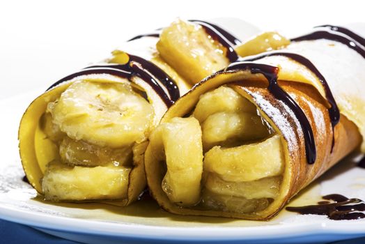 Delicious freshly baked pancakes or crepes filled with banana and drizzled with chocolate fort a gourmet dessert