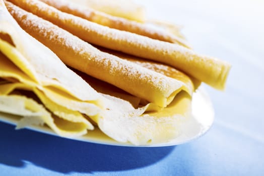 Freshly baked golden pancakes or crepes neatly folded in a plate