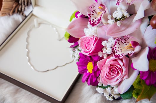 Beautiful flower bouquet and a white gold necklace placed in a shape of heart as a every woman gift wish