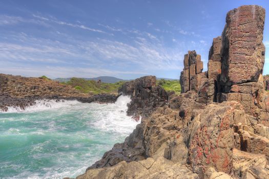 A fair swell at Bombo kicked up large waves that smashed the  clusters of hexagonal basalt columns which are an internationally recognised geological phenomena formed from volcanic action. The sun highlights the red-brown colour (due to oxidisation of haematite) of the sandstone which contrasts the grey-black latite which displays spectacular columnar jointing.