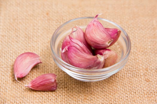 Garlic in glass bowl on placemat jute