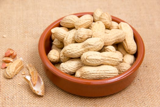 Peanuts in rustic bowl on jute mat