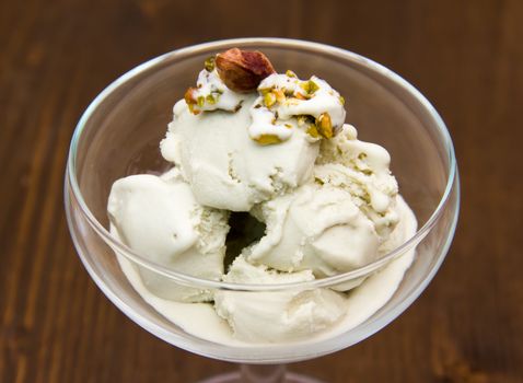 Pistachio ice cream in bowl on wooden table