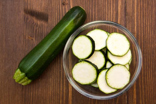 Zucchini slices on bowl on wooden table top views
