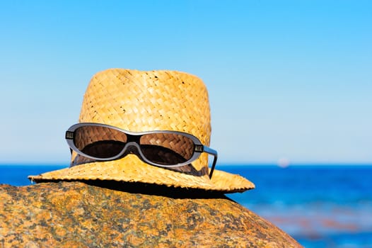 Straw hat with glasses on the coast