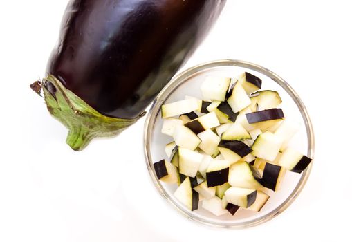 Cubes of eggplant on bowl on white background seen from above