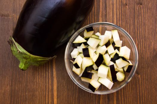 Cubes of eggplant on bowl on wooden table seen from above