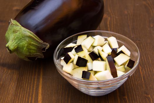 Cubes of eggplant on bowl on wooden table