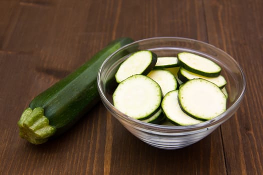 Zucchini slices on bowl on wooden table