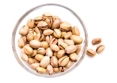 Pistachios on glass bowl on a white background seen from above