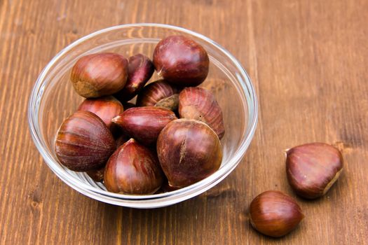 Glass bowl with chestnuts on wooden table