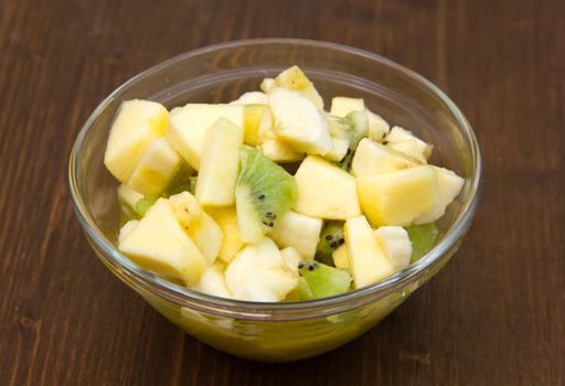 Bowl with fruit salad on wooden table