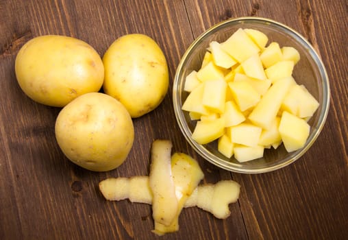 Bowl with potato cubes on wooden table top view