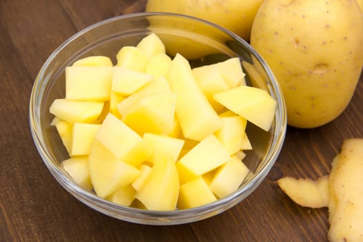 Bowl with potato cubes on wooden table