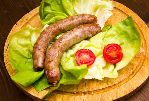 Sausage on cutting board with salad on wooden table