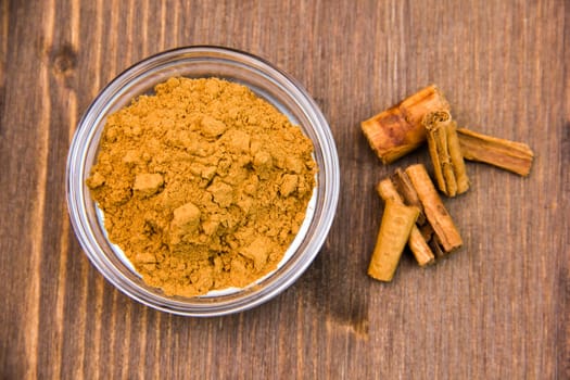 Bowl with cinnamon on wooden table top view