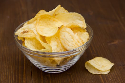 Bowl of chips on wooden table close up view