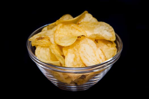 Bowl with potato chips on a black background