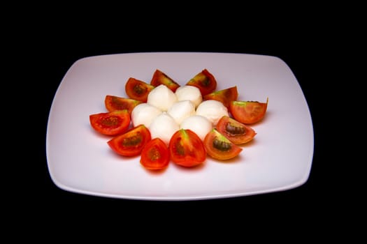 Plate with mozzarella and tomato on a black background