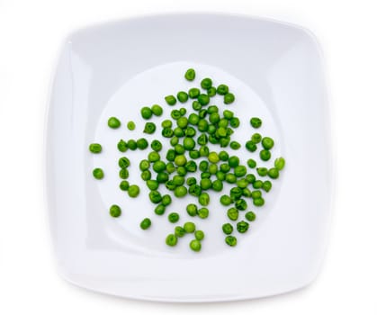 Plate with cooked green peas on a white background seen from above