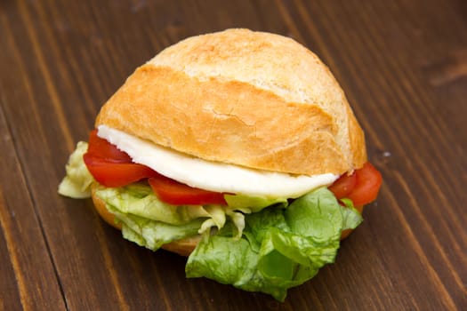 Sandwich with cheese and tomatoes on wooden table