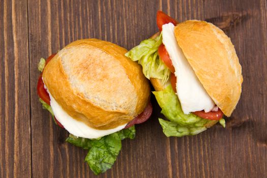 Sandwiches with cheese and tomatoes on wooden table seen from above