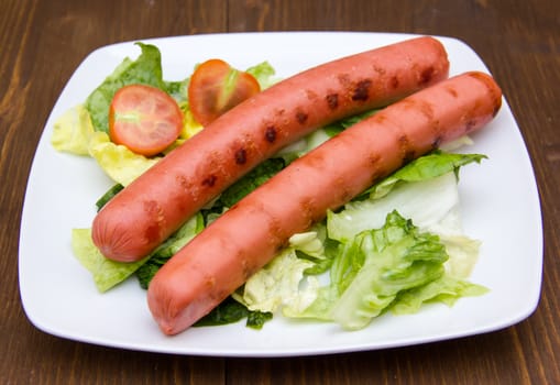 Sausages with salad on plate on wooden table