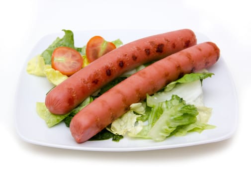 Sausages with salad on plate on white background