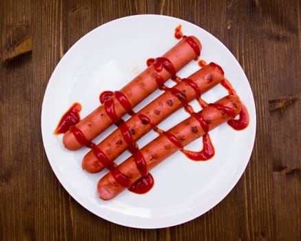 Sausages with tomato sauce on wooden table seen from above