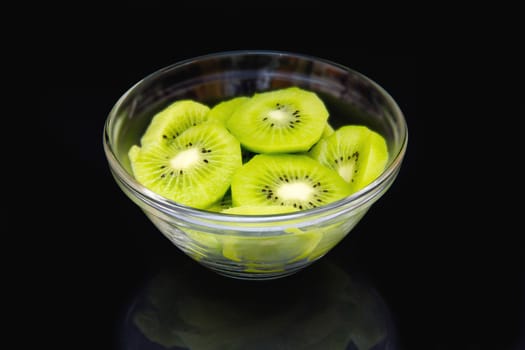 Slices of kiwi fruit on bowl on a black background