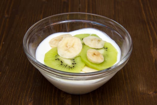 Yogurt with kiwi and banana on wooden table