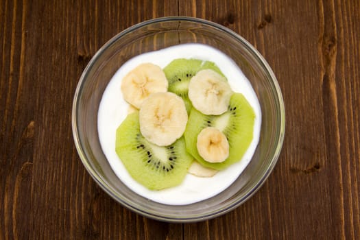 Yogurt with kiwi and banana on wooden seen from above