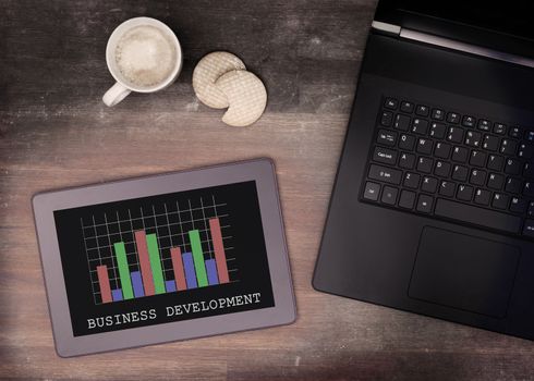 Tablet touch computer gadget on wooden table, graph, vintage look