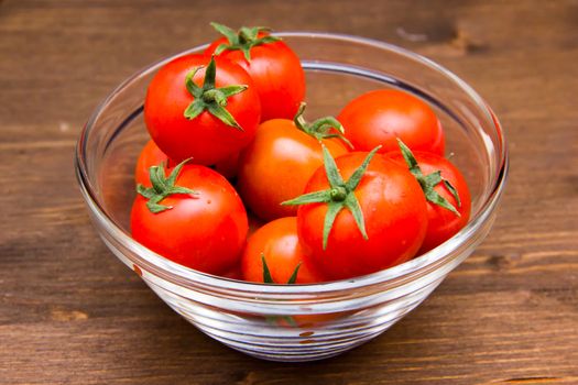 Glass bowl with tomatoes on wooden table