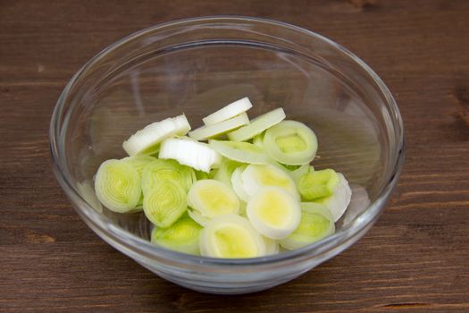 Bowl with sliced leek on wooden table