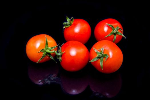 Cherry tomato that is reflected on a black background