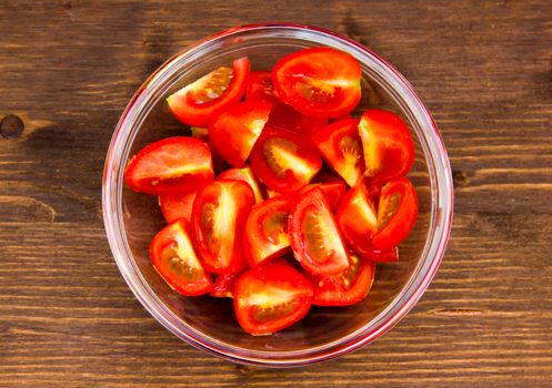 Wedges of tomato bowl on wooden table seen from above