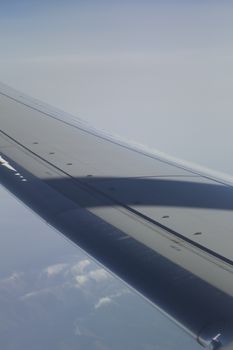 Airplane flying in sky in flight metal wing.