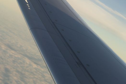 Airplane flying in sky in flight metal wing.