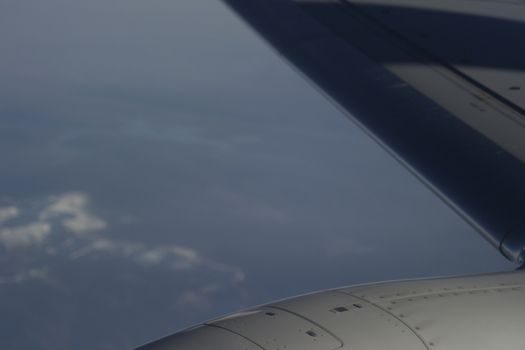 Airplane flying in sky over land in flight engine wing.