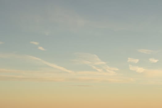 Sky with clouds in blue and pink purple sunset evening pastel colors photo shot from an airplane in flight flying above the cloud level.